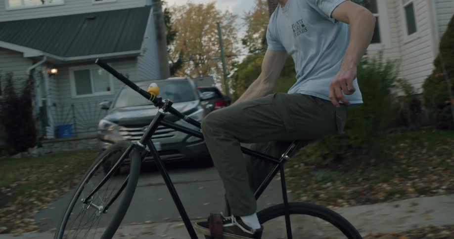 Man doing tricks on a bicycle rides on a calm neighborhood at morning