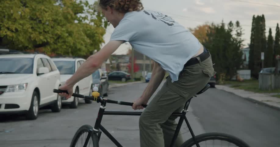 A man does a jump and turn trick on his bicycle while riding through a neighborhood