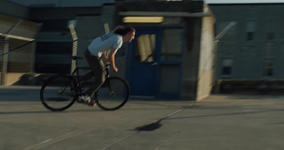 A man rides his bicycle through a parking lot with views of downtown