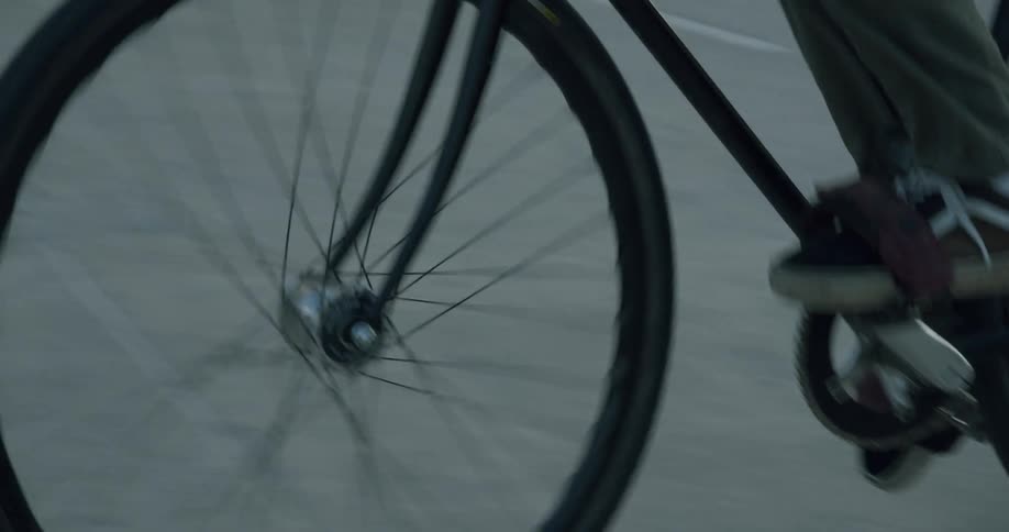 A man rides his bicycle through a parking lot