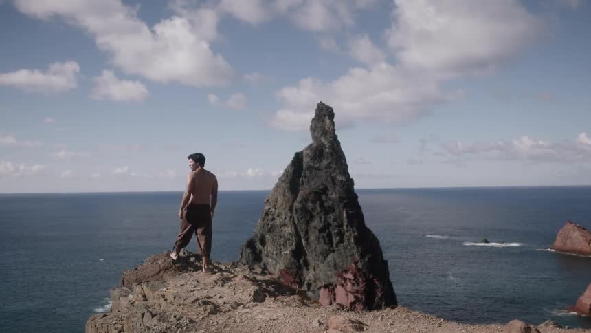 Man standing atop a rocky area overlooking the sea