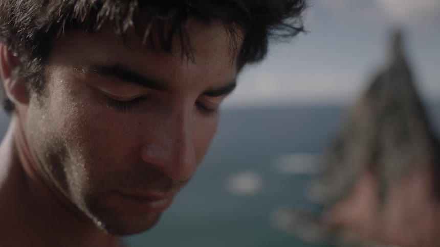 A man is looking down by the water on a windy day