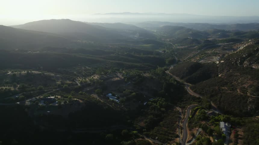 An aerial view of a valley with a road running through it surrounded by rolling hills