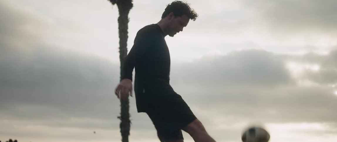 A man is kicking a soccer ball up with his feet