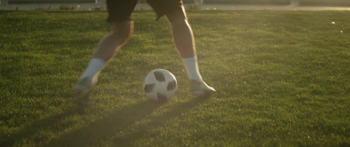 A man kicking a soccer ball runs down a field