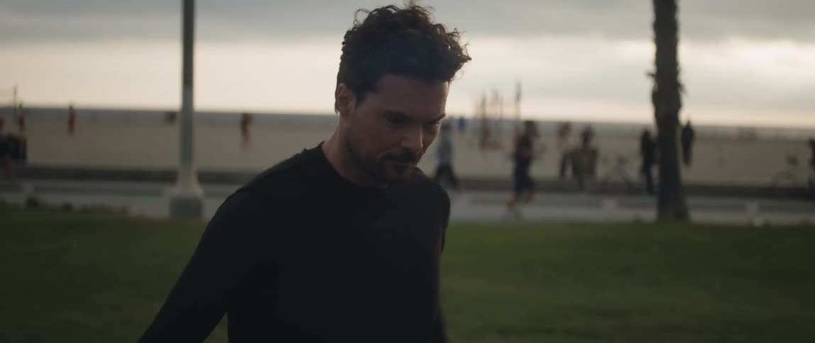 A man juggles a soccer ball with his legs and head on a beach on a cloudy day