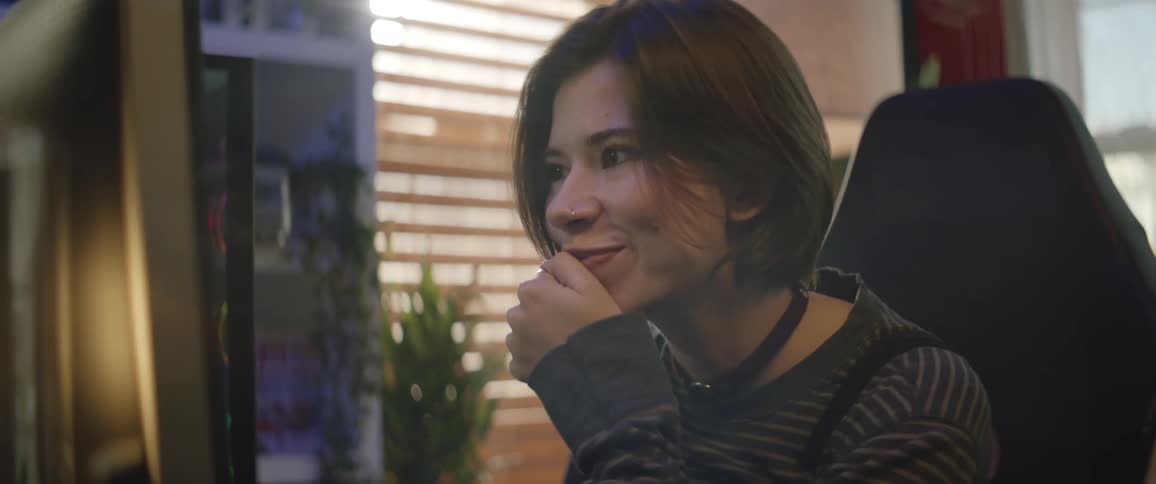 A woman smiles as she looks at her computer