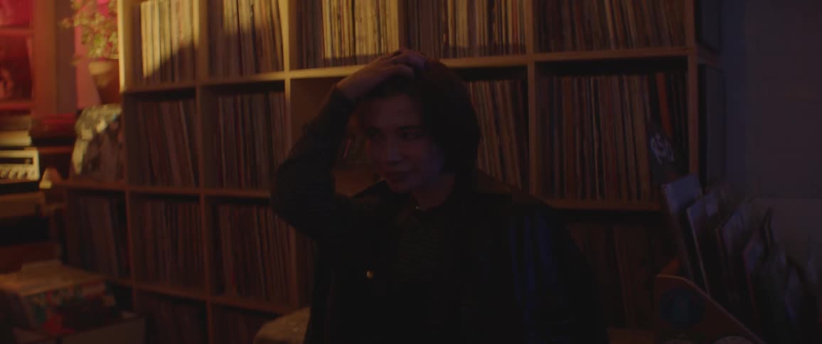 A teenage girl smiling and bopping her head while sitting indoors