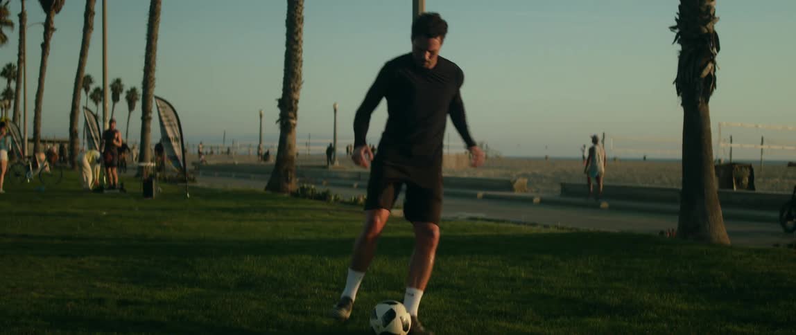 A man kicks a soccer ball up into the air practicing his footwork at the beach