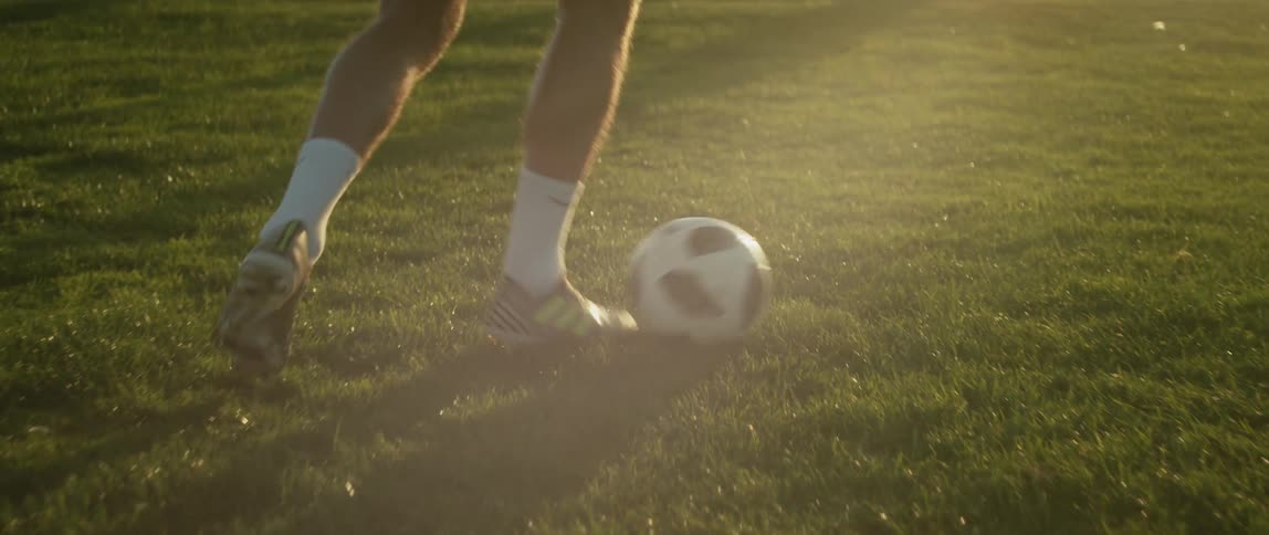 A man kicks a soccer ball as he runs down a field