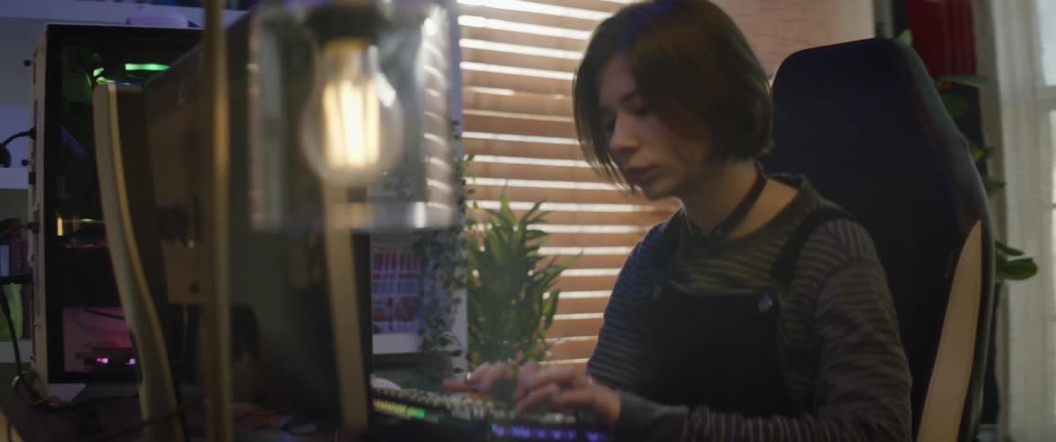 A teenage girl typing on a desktop computer