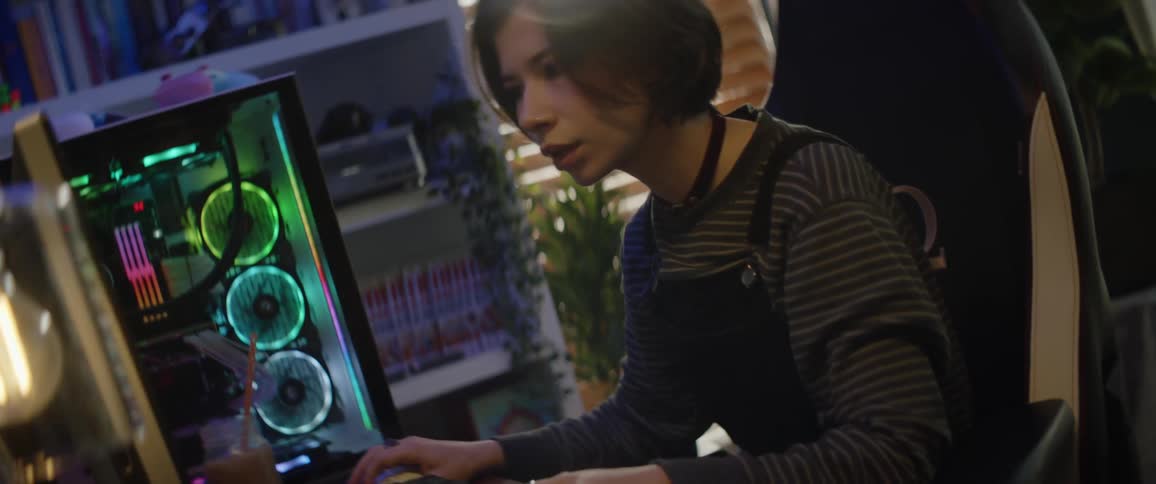 A teenage girl sits in front of a computer at home and types