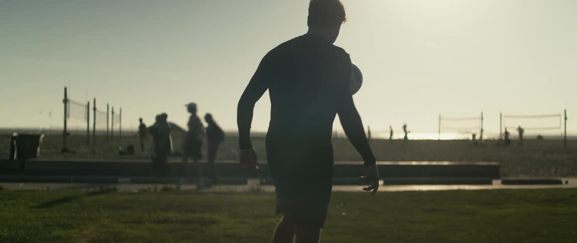 A man kicking around a soccer ball near a beach