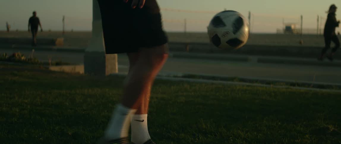 Close up of the legs of a man practicing with a soccer ball at park in the late afternoon