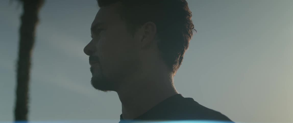 A man outside looks off in to the distance as the sun shines down