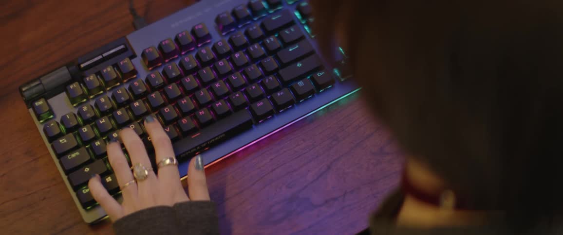 A teenage girl is sitting at a desk typing on a computer keyboard