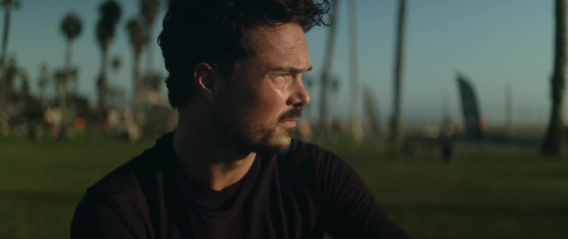 Close up of the face of a young man standing on a park waiting at evening