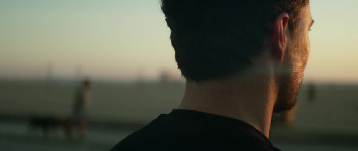 A man looking out towards a beach at sunset