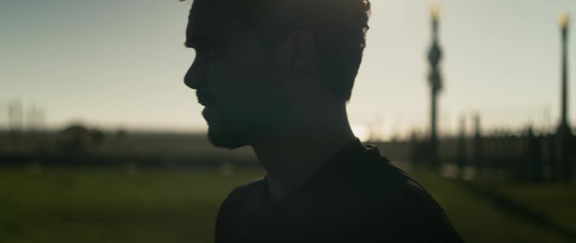 Silhouette of a young relaxed man standing on a soccer field at morning