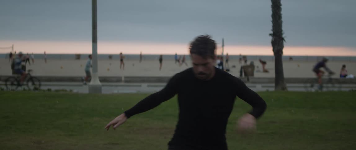 A man jogs on the grass and dodges obstacles while working out at Venice Beach
