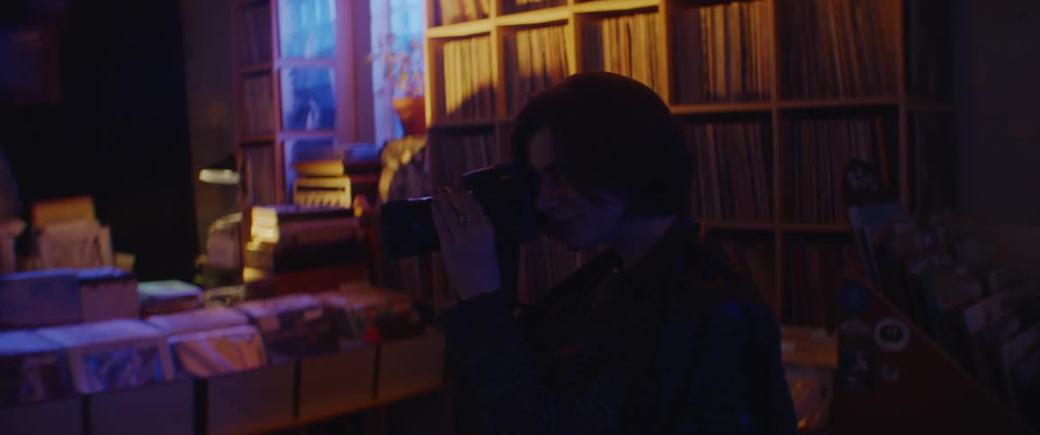 A teenage girl walks through a record store and takes photos
