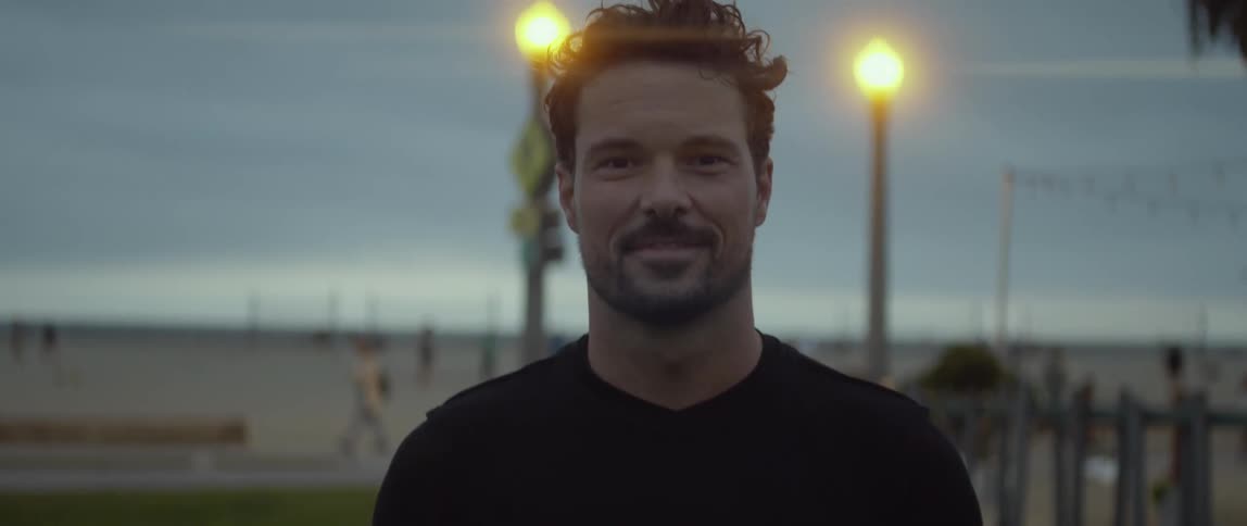 A man tossing around a soccer ball while smiling outside