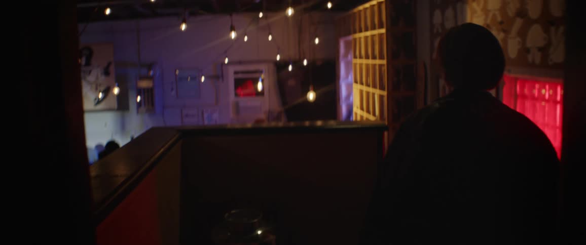 Silhouette of a woman entering a nightclub where a live band performs on stage in front of public