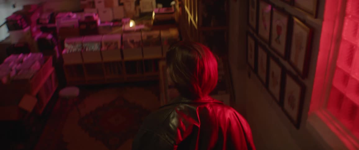 Woman walks down stairs into room with several boxes full of records while a guitarist plays nearby
