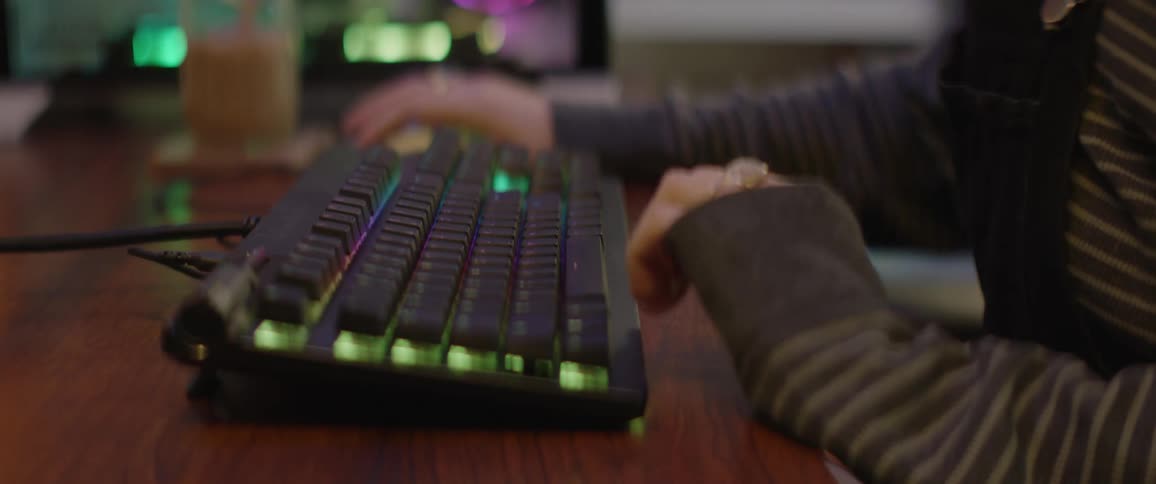 Close up of a woman at a desk pulling a keyboard forwards and typing