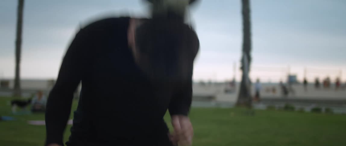 Young man playing with a soccer ball on a park near a beach at sunset