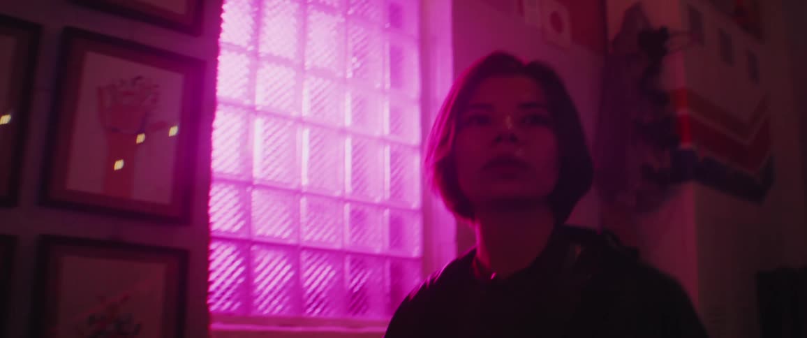 A woman smiles as she walks down the steps and enters a room with colorful lights flashing and glowing
