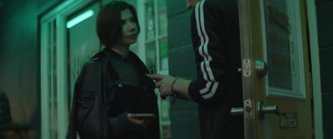 Woman shows smartphone to man at business who scans the screen before letting her in