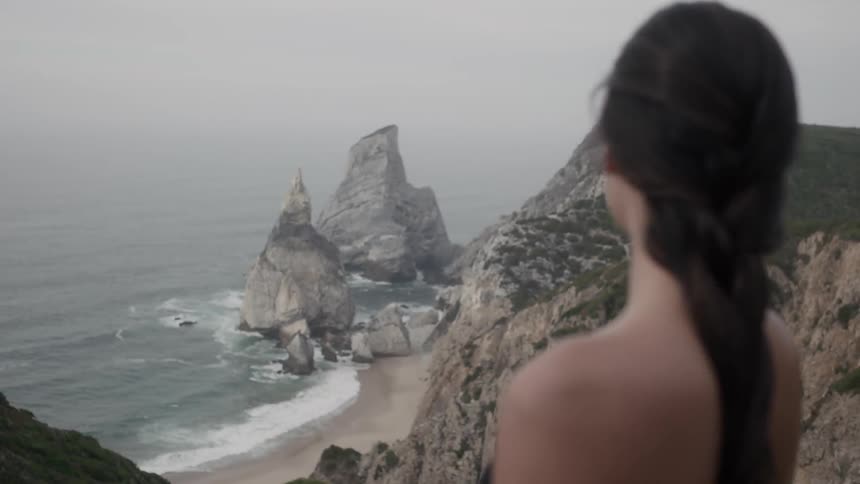 A woman stand on cliffs looking out over the ocean