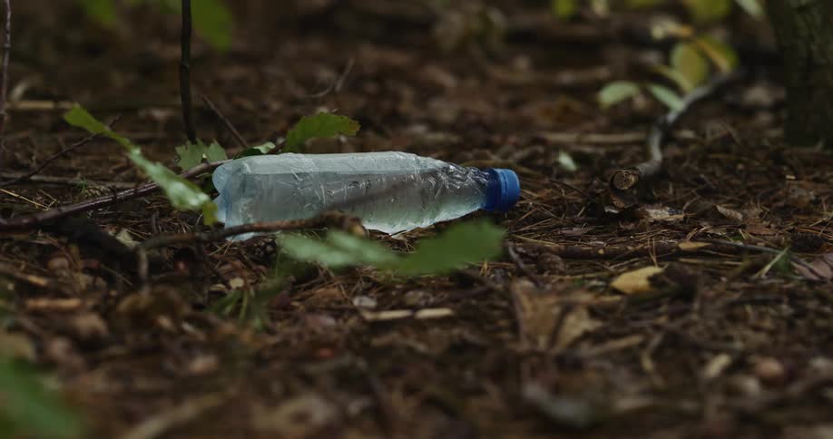 Full water bottle lies on dirt on ground