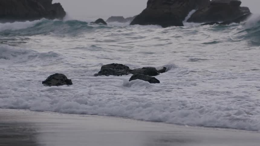 Small waves coming up on a rocky shore