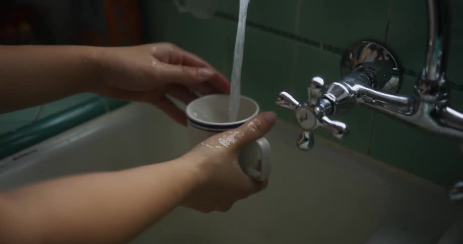 A woman washes a mug at home