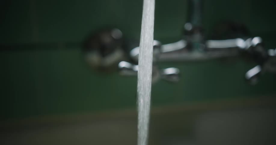 A woman reaches over and turns on the hot water faucet and steam rises as the hot water flows