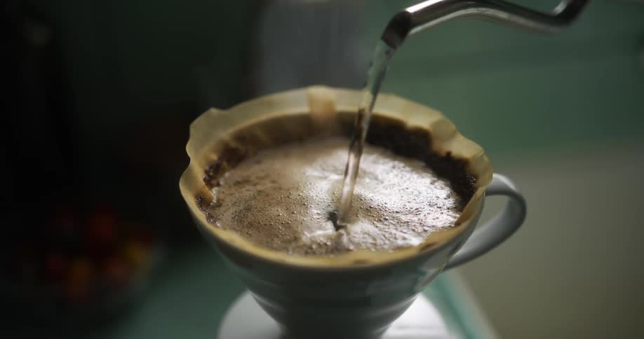 Hot water is being poured into cup to make coffee