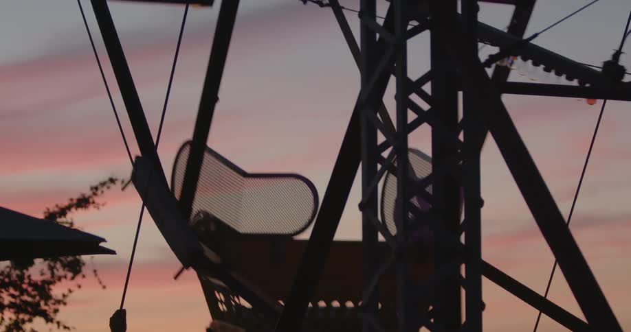 A man and woman ride on a ferris wheel as the sun sets