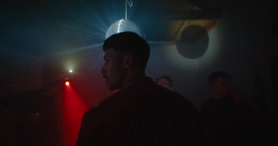 A man walks into a club and looks around as strobing lights flash around him