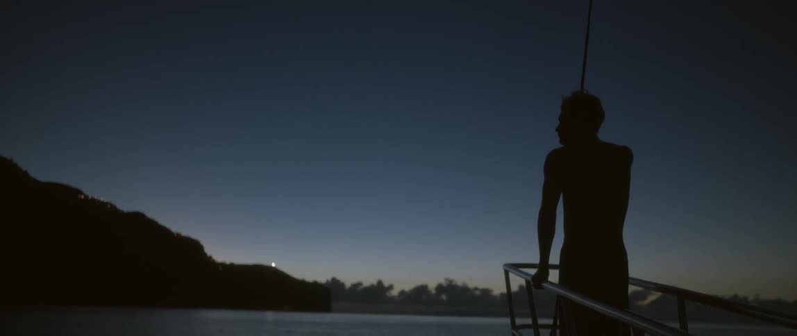 A man is standing on the front of a boat watching out over the water
