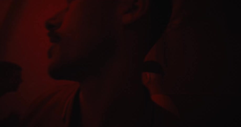 Man with mustache and jacket dances in red light in the club