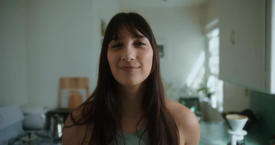 A woman is smiling and standing in her kitchen