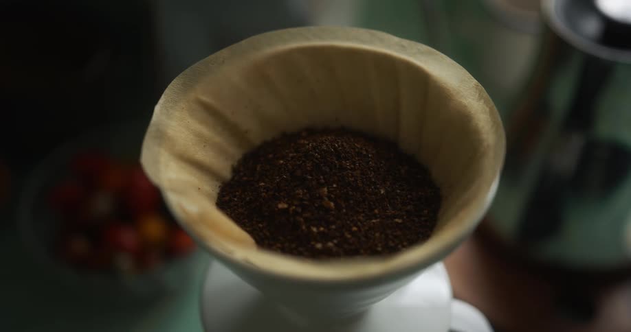 A person is making a pot of coffee indoors