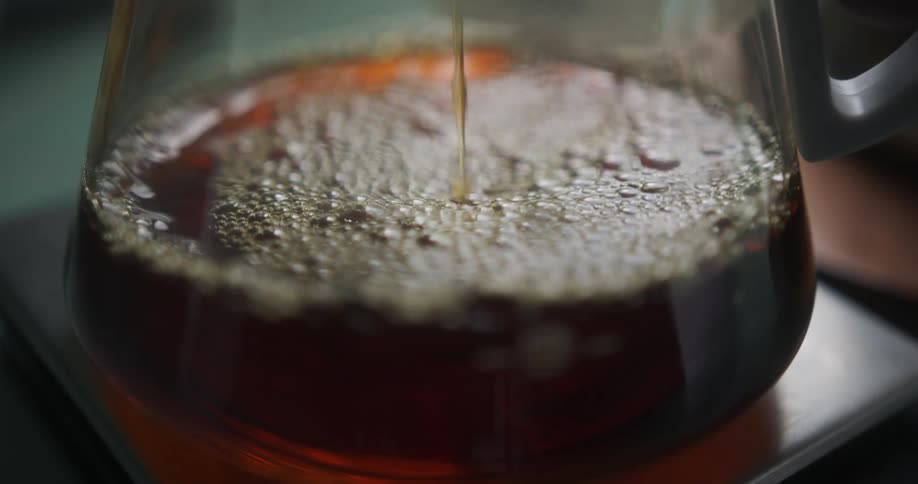 Coffee drips into a coffee pot on a pedestal
