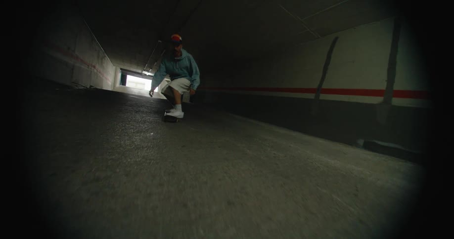 A man is riding his skateboard through a parking garage as he turns the board with his feet