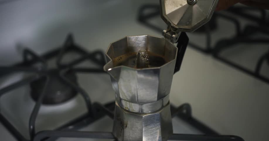 A woman lifts a lid as coffee brews
