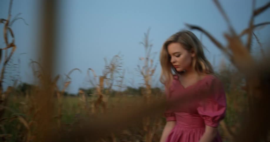 A woman walks through a field of corn