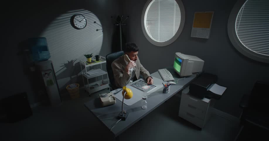 A man answers the phone in frustration while sitting at his desk