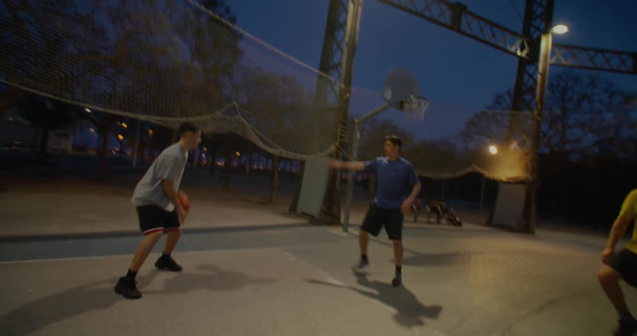 A small group of men are playing basketball in a park